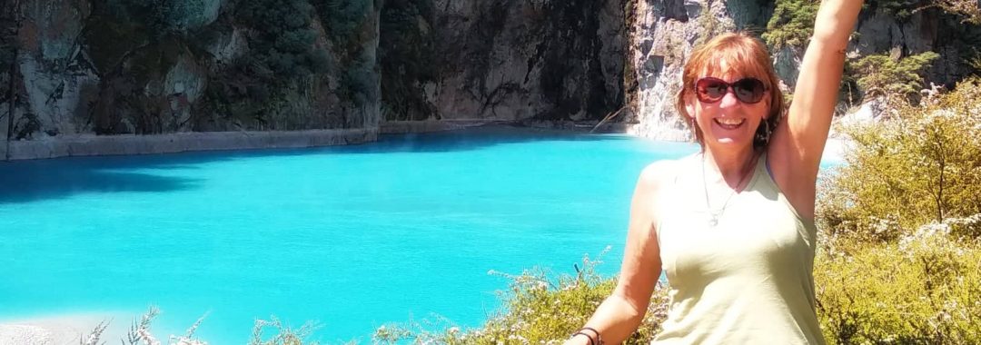 Jane Clements Life Coach in front of a bright blue volcanic lake